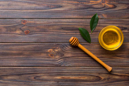 Honey jar with wooden honey dipper on white background top view with copy space. Delicious honey bottle.の写真素材