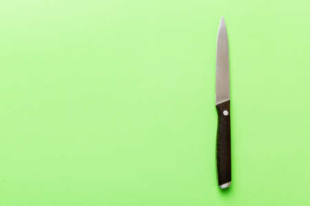 A simple kitchen knife with wooden handle, top view isolated on green background.