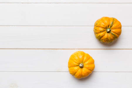 Autumn composition of little orange pumpkins on colored table background. Fall, Halloween and...