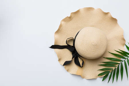 Summer holidays. Summer concept with straw hat and tropical leaf. Flat lay, top view, copy space.