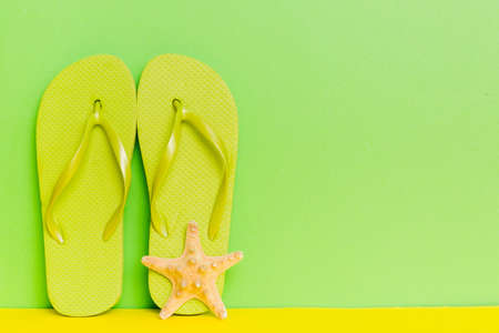 beach accessories. Flip flops and starfish on colored background. Mock up with copyspace.の写真素材