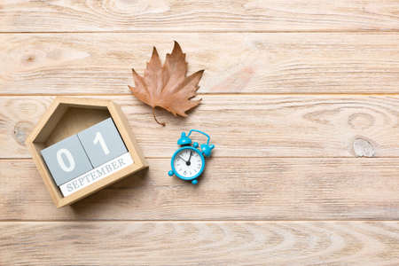Calendar for September top view with copy space. Wooden calendar block with date 1 September with falling autumn leaves background.の写真素材