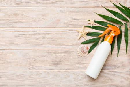 Sunscreen spray bottle. Bottle with sun protection cream and sea shells with tropical green leaf on...