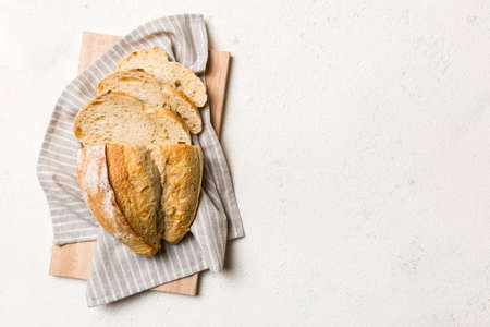 Freshly baked bread slices on cutting board against white wooden background. top view Sliced bread.