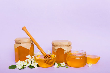 robinia honey bollte with acacia blossoms on colored table.