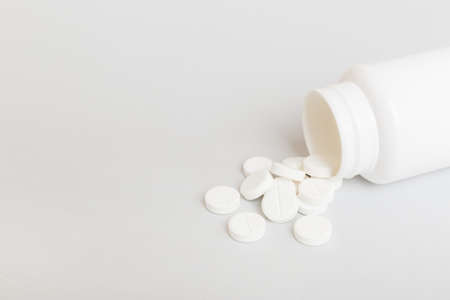 different drugs and health supplement pills poured from a medicine bottle health care and medical top view on colored background.の写真素材