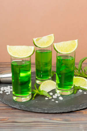 Sweet refreshing mint liqueur, with ice and mint leaves on table background, Shots with lime slice and mint flat lay.の写真素材