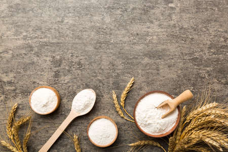 Flat lay of Wheat flour in wooden bowl with wheat spikelets on colored background. world wheat...