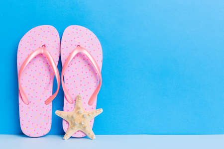 beach accessories. Flip flops and starfish on colored background. Mock up with copyspace.の写真素材