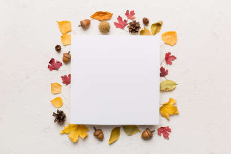 Autumn composition with paper blank and dried leaves on table. Flat lay, top view, copy space.