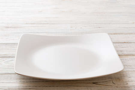 Perspective view of empty square plate on wooden background. Empty space for your design.の写真素材