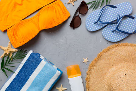 Woman swimwear and beach accessories flat lay top view on colored background Summer travel concept. bikini swimsuit, straw hat and seasheels. Copy space top view.の写真素材