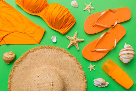 Woman swimwear and beach accessories flat lay top view on colored background Summer travel concept. bikini swimsuit, straw hat and seasheels. Copy space top view.の写真素材