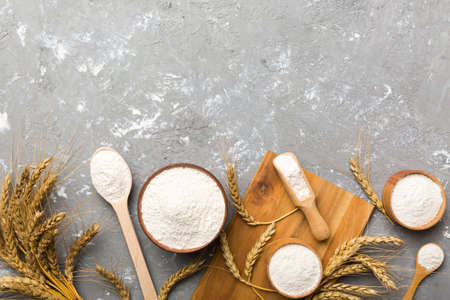 Flat lay of Wheat flour in wooden bowl with wheat spikelets on colored background. world wheat...
