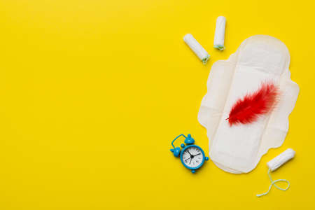 Ringing alarm clock with sanitary female tampons and menstrual sanitary pads. Medical concept of woman critical days and menstruation. Female daily hygiene. copyspace.の写真素材