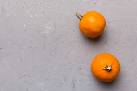 Autumn composition of little orange pumpkins on colored table background. Fall, Halloween and...