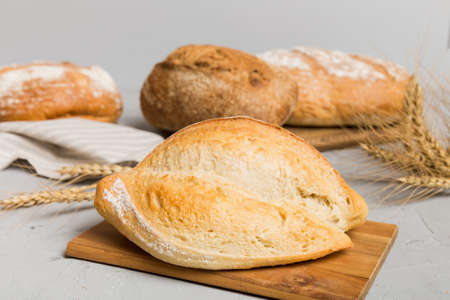 Freshly baked bread on cutting board against white wooden background. perspective view bread with...