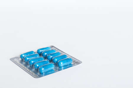 Blister package with Vitamin on color background. Medicine pills on a light background. Medicines and prescription pills flat lay background. blue medical tablets in blister.の写真素材