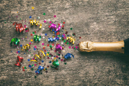 Creative flat lay composition with bottle of champagne and space for text on color background. Champagne bottle with colorful party streamers. holiday or christmas concept.の写真素材