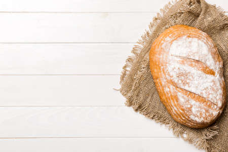 Freshly baked delicious french bread with napkin on rustic table top view. Healthy white bread loaf.