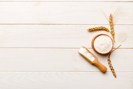 Flat lay of Wheat flour in wooden bowl with wheat spikelets on colored background. world wheat crisis.の写真素材