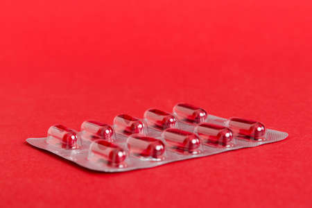 Blister package with Vitamin a on color background. Medicine pills on a light background. Medicines and prescription pills flat lay background. red medical tablets in blister.の写真素材