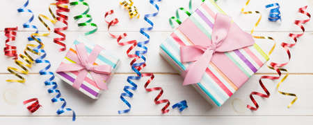 Holiday flat lay with gift boxes wrapped in colorful paper and tied decorated with confetti on colored background. Christmas, Birthday, Valentine and sale concept, top view.の写真素材