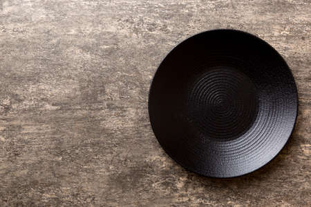 Top view of black plate on cement background. Empty space for your design.の写真素材