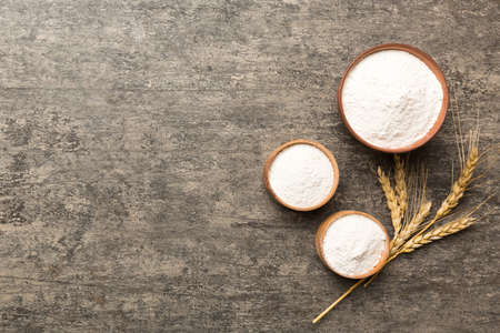 Flat lay of Wheat flour in wooden bowl with wheat spikelets on colored background. world wheat crisis.の写真素材