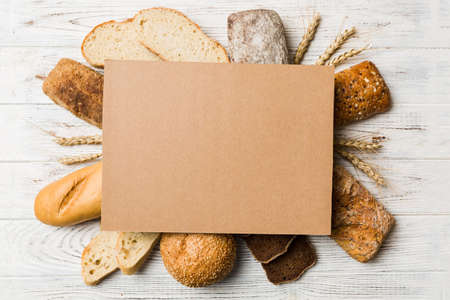Minimalist paper blank mockup on background of Types of homemade bread. Different kinds of fresh bread as background, top view with space for your text or design.の写真素材