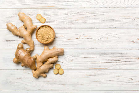 Finely dry Ginger powder in bowl with green leaves isolated on colored background. top view flat...