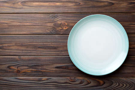 Top view of empty blue plate on wooden background. Empty space for your design.の写真素材
