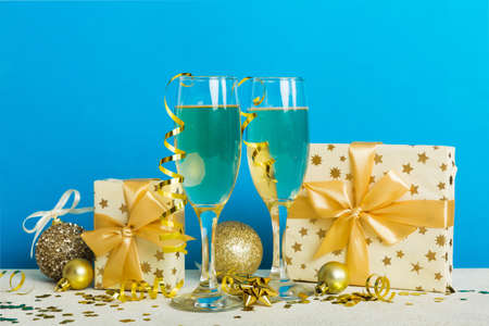 Champagne glasses and christmas decor on colored holiday background. Flat lay New Year decorations.の写真素材