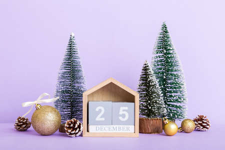 December 25th. Christmas composition on colored background with a wooden calendar, with a gift box, toys, bauble copy space.の写真素材