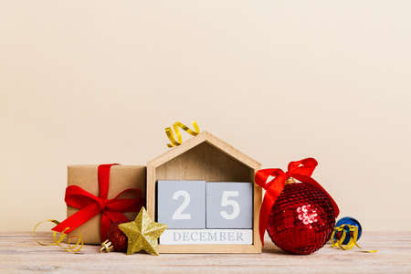 December 25th. Christmas composition on colored background with a wooden calendar, with a gift box,...