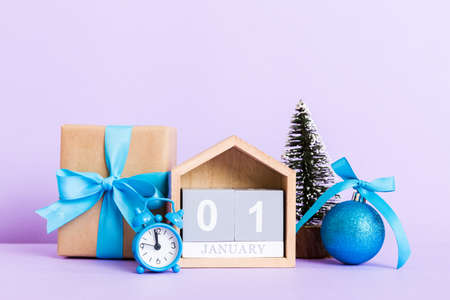 Christmas composition on colored background with a wooden calendar, with a gift box, toys, bauble...
