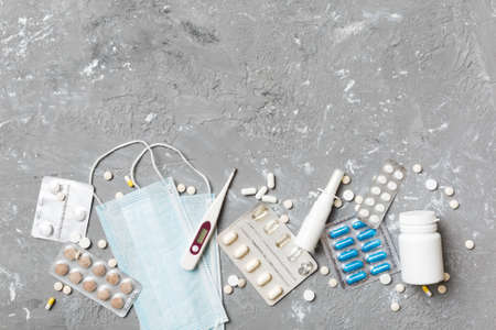 Protective face masks or surgical masks, medicine pills and thermometer on table background.