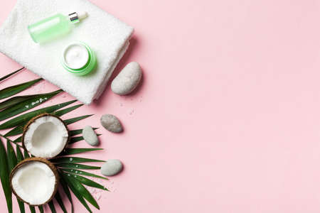 Coconut with jars of coconut oil and cosmetic cream on colored background. top view. Free space for your text. Natural spa coconut cosmetics and organic treatment concept Coconut Spa composition.の写真素材