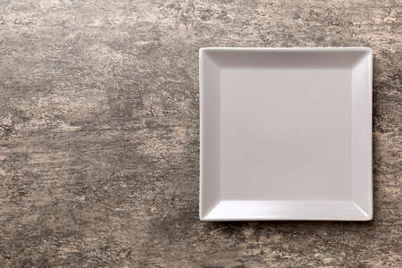 Top view of empty square plate on cement background. Empty space for your design.の写真素材