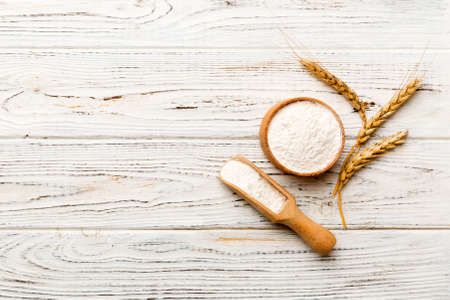 Flat lay of Wheat flour in wooden bowl with wheat spikelets on colored background. world wheat crisis.の写真素材