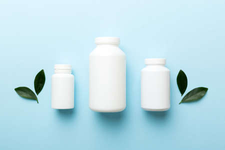 supplement pills with medicine bottle health care and medical top view. vitamin tablets. Top view mockup bottle for pills and vitamins with green leaves, natural organic bio supplement, copy space.の写真素材