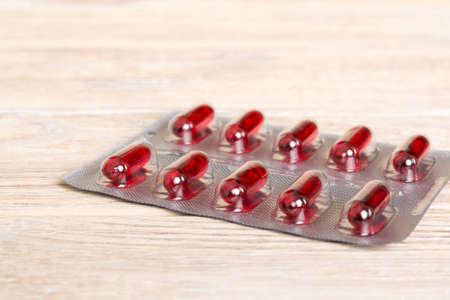 Blister package with Vitamin a on color background. Medicine pills on a light background. Medicines and prescription pills flat lay background. red medical tablets in blister.の写真素材