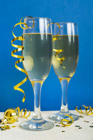 Champagne glasses and christmas decor on colored holiday background. Flat lay New Year decorations.