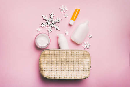 Christmas flat lay with makeup cosmetic products in cosmetic bag on colored background. Top view New year beauty concept.の写真素材