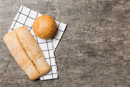 Assortment of freshly baked bread with napkin on rustic table top view. Healthy unleavened bread. French bread.の写真素材