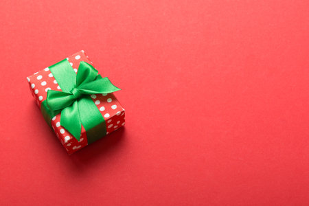 Wrapped christmas or other holiday handmade present in paper with colored ribbon. Present box, decoration of gift on table, top view with copy space.の写真素材