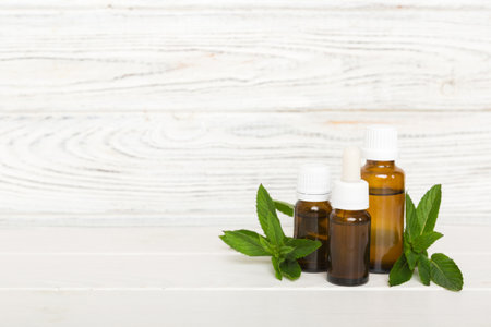 Natural Mint Essential Oil in a Glass Bottle. organic cosmetics with herbal extracts of mint on colored background.の写真素材