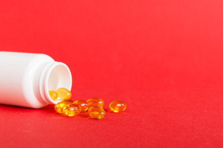 Soft gels pills with Omega-3 oil spilling out of pill bottle close-up. Gel capsule bottles white...