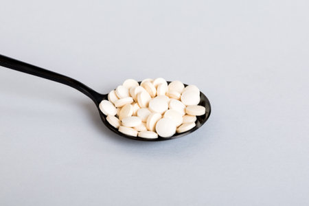 Heap of white pills on colored background. Tablets scattered on a table. Pile of red soft gelatin capsule. Vitamins and dietary supplements concept.の写真素材