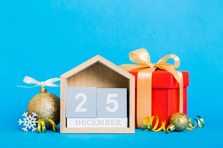 December 25th. Christmas composition on colored background with a wooden calendar, with a gift box,...